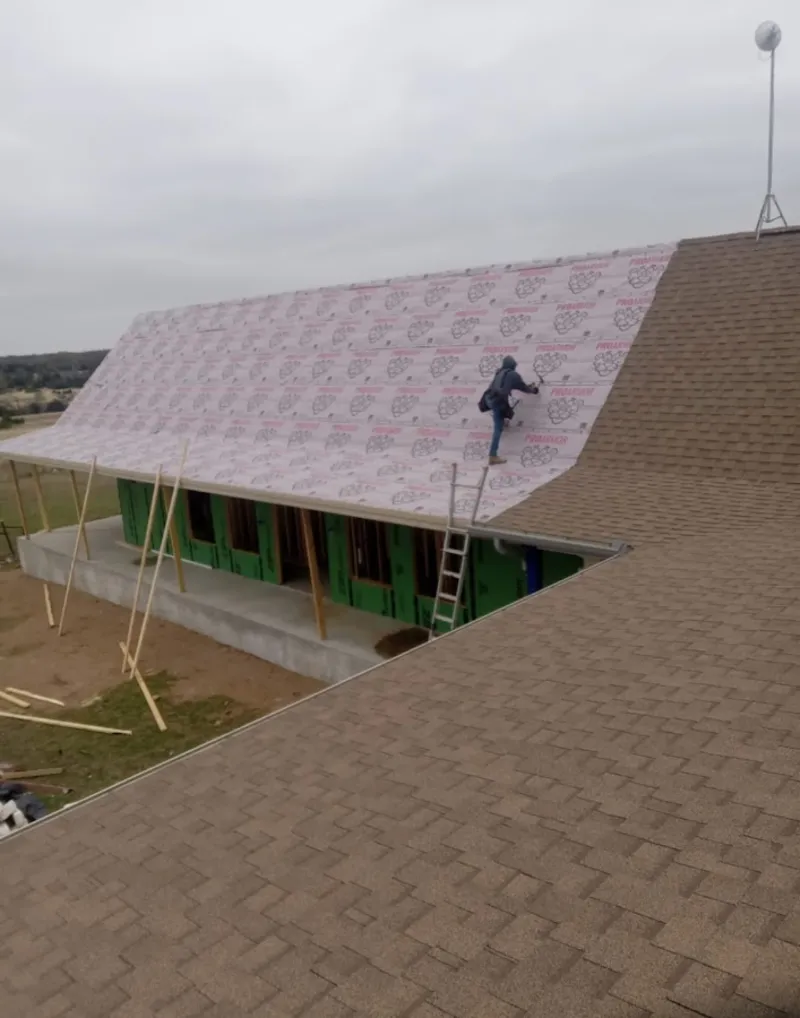 Worker preparing underlayment for a metal roof installation in St. Peters